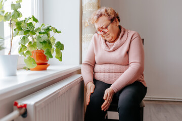 Painful Struggle An Overweight Woman Suffers with Leg Pain at Home, A senior woman holding onto her...