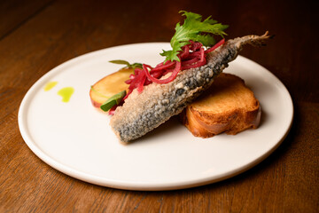 plate of fried fish garnished with onion and lemon and toast on table
