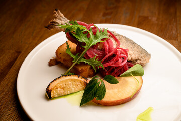 tasty fried fish garnished with onion and lemon and toast on plate on table