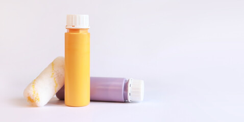 Interior renovation paint. Paint in plastic bottles and paint roller on a white background. Free space for text. Two bottles of acrylic paint, photo for banner
