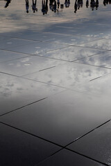 Silhouettes in a wet square at dusk.