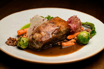 Close-up view on dish of piece of baked pork meat with buckwheat and vegetables on plate