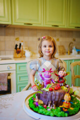 little girl with a large cake with figures of fairy-tale characters