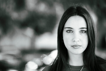 beautiful face of white italian young girl with black hair in a black and white close-up portrait