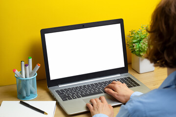 A woman uses a laptop computer with a blank white screen on the desktop.