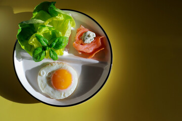 top view of healthy ketogenic breakfast with fried egg, green salad and smoked salmon