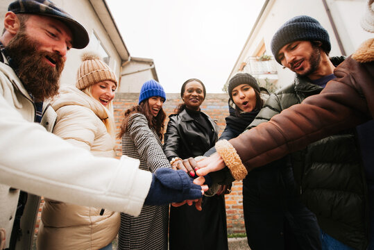 Happy group of multiracial people stacking hands outdoors. Community and unity concept