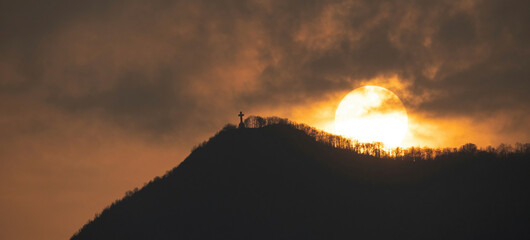 Image of the cross on top of Mount Musinè with a sun frame 