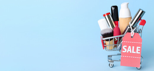 Shopping cart with makeup cosmetics and accessories for sale on light blue background with space for text © Pixel-Shot