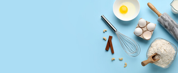 Different ingredients and utensils for baking on light blue background with space for text
