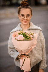 bouquet of pink roses in wrapping paper in the hand of attractive woman