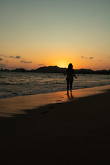 Naklejka premium beautiful woman enjoying the beach and an incredible sunset against light