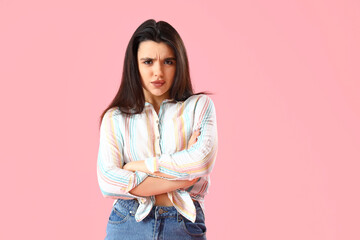 Upset young woman in shirt on pink background
