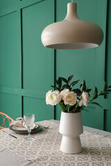 Vase with ranunculus flowers on dining table in room