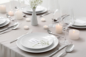 Setting for Mother's Day celebration with gypsophila flowers and burning candles on table