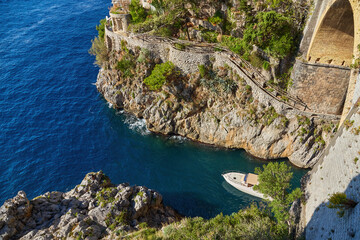 famous Furore fiordseen from the beach with boats floating under the arch.