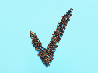 Check mark made of peppercorns on blue background