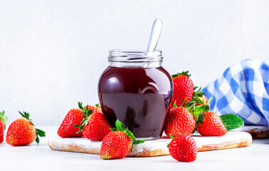 Strawberry jam in glass jar and fresh berries, white table background, copy space