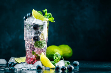 Blueberry Mojito cocktail drink with lime, white rum, soda, cane sugar, mint, and ice in glass on...
