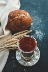Bread, wine and ears of wheat on a dark background, communion concept