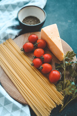 Italian food cooking-tomatoes, basil, pasta and cheese on stone background, top view, copy space