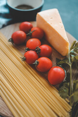 Italian food cooking-tomatoes, basil, pasta and cheese on stone background, top view, copy space