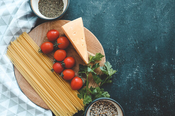Italian food cooking-tomatoes, basil, pasta and cheese on stone background, top view, copy space