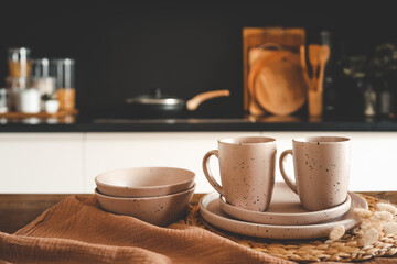 Set of beige minimalist dishes on a table against the backdrop of a kitchen