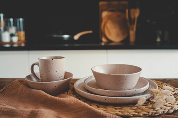 Set of beige minimalist dishes on a table against the backdrop of a kitchen
