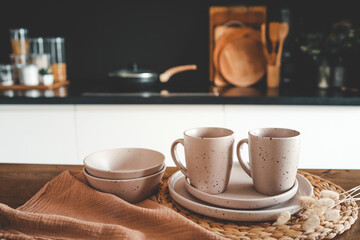 Set of beige minimalist dishes on a table against the backdrop of a kitchen