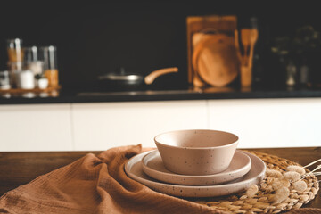 Set of beige minimalist dishes on a table against the backdrop of a kitchen