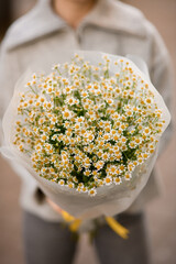 selective focus on white small camomile flowers in bouquet in wrapping paper