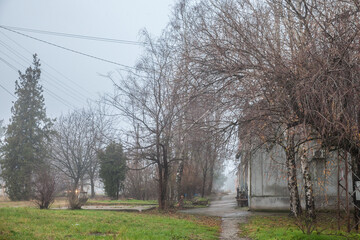 Selective blur on an empty road and street in the village of Vladimirovac in Vojvodina, Banat, Serbia, in the countryside, with a smog and fog during a cold freezing afternoon of winter.