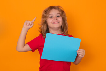 Fototapeta na wymiar Kid boy showing blank banner on yellow background, pointing up. Advertising billboard, placard. Child hold empty color blank sheet of paper, copy spase. Poster for your text information.