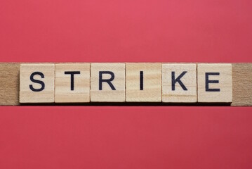 text the word strike from gray wooden small letters with black font on an red table
