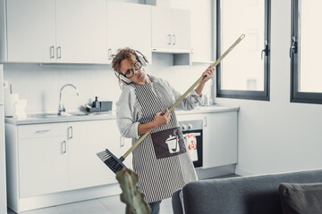 Carefree happy young woman cleaning house living room have fun dancing with mop, smiling overjoyed...