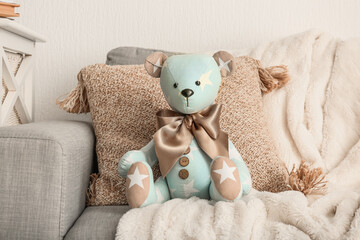 Toy bear with pillow and plaid on sofa in living room