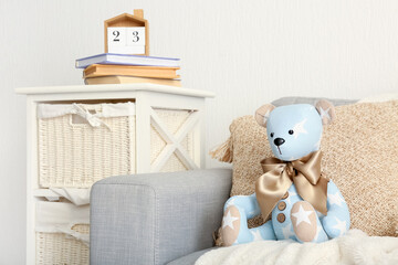 Toy bear with pillow and plaid on sofa in living room