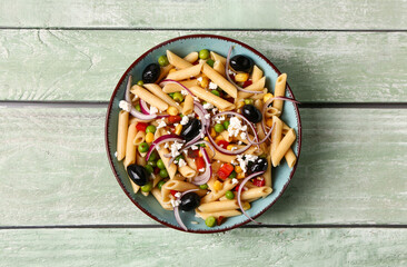 Bowl with tasty pasta salad on light wooden background