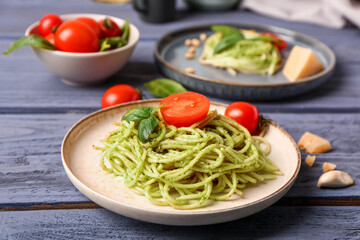 Plates with tasty pesto pasta and tomatoes on color wooden background
