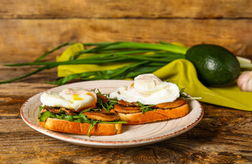 Plate with tasty eggs Benedict on wooden background