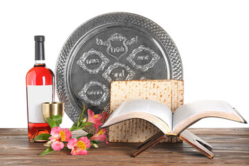Torah, bottle of wine, Passover Seder plate, flatbread matza and alstroemeria flowers on wooden table against white background