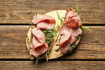 Board of tasty bruschettas with ham on wooden background