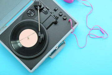 Fototapeta premium Record player with vinyl disk and headphones on blue background