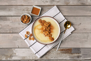 Bowl of tasty semolina porridge with nuts on wooden background