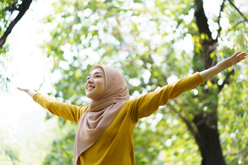 Happy cheerful Asian beautiful female muslim practicing an exercise and stretching at the park close up with copyspace. Modern muslim woman lifestyles and diversity concept.