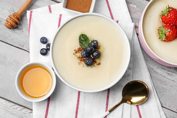 Bowl of tasty semolina porridge with blueberry and strawberry on wooden background