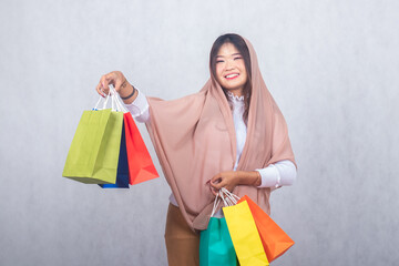 Fototapeta na wymiar hijab girl smiles slightly lifting the right hand paperbag shopping. portrait Asian Chinese Muslim Muslim hijab headscarf woman fasting Ramadan on Eid Al-Fitr day with white background.