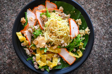 yellow noodles Thai food - dried noodles food on plate with condiment minced pork lemon lime peanuts dumpling red pork on plate