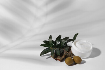 Jar of natural cream, stones and olives on white background, space for text. Cosmetic products